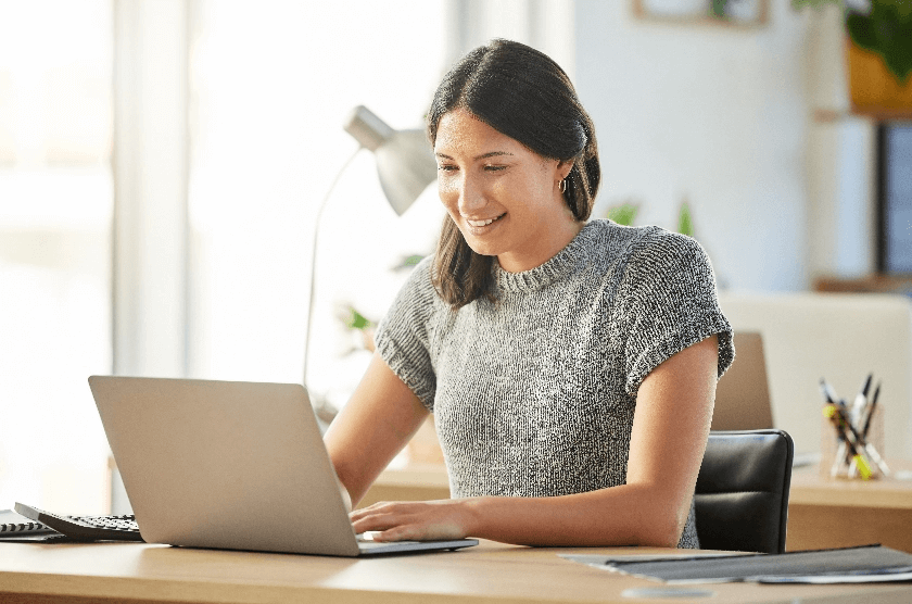 A woman smiling and typing on a laptop