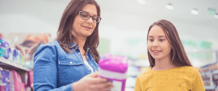A woman showing a girl a period product