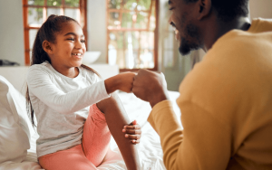A father holding the hand of his daughter who is smiling