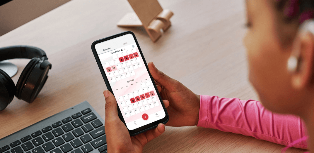 A girl holding a smartphone that is showing Menstruation Nation app