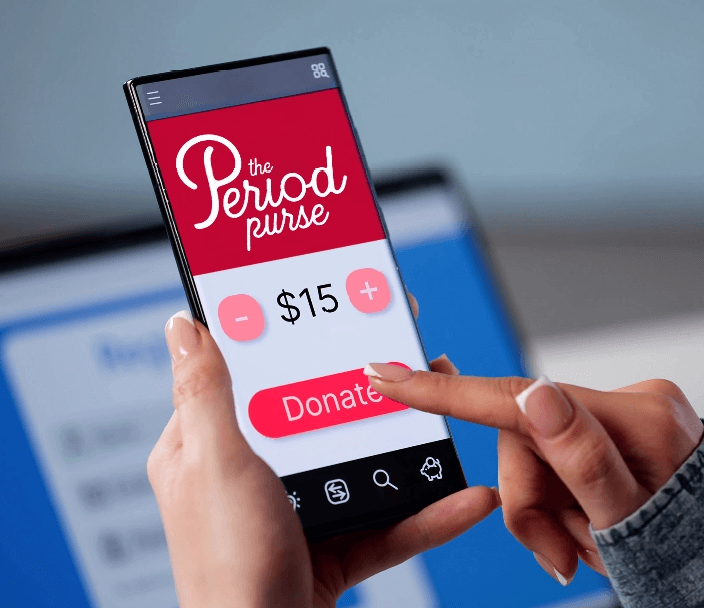 A person pressing the donate button on her mobile phone while on The Period Purse donate page, showing 15 dollars as the donation amount
