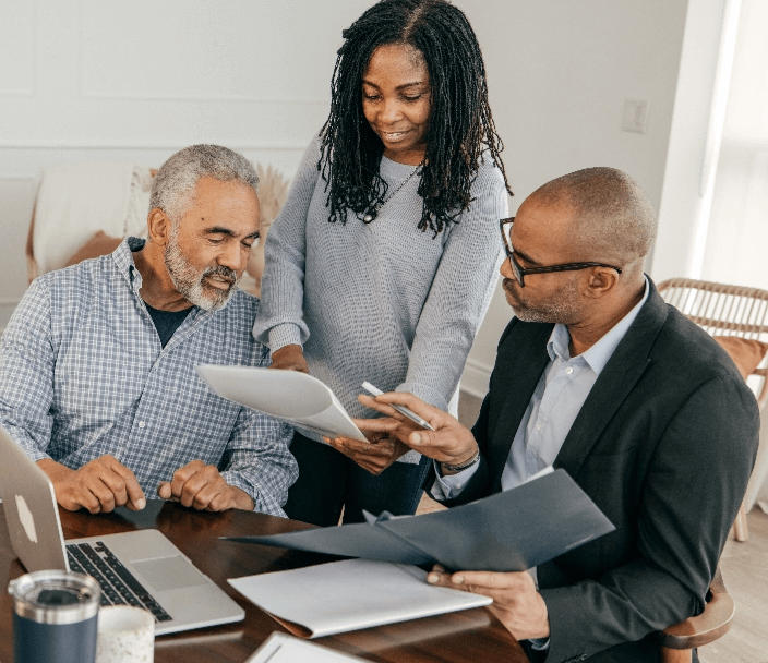 A woman pointing to paper and two seniors looking at it