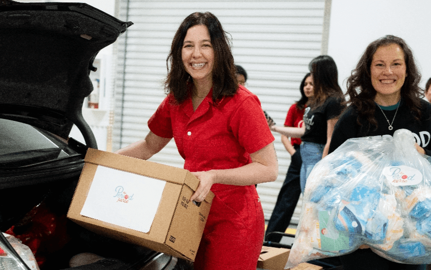 A woman smiling and loading a box into a car
