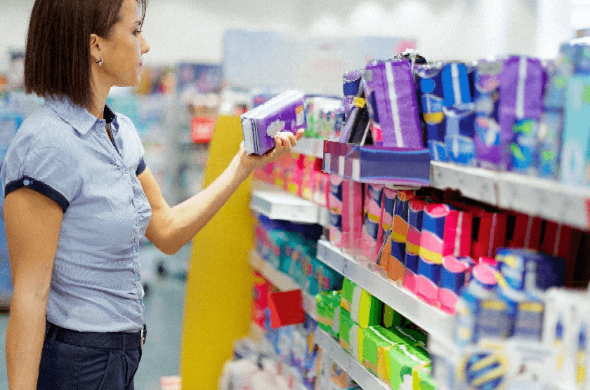 A woman choosing a sanitary product from a store shelf