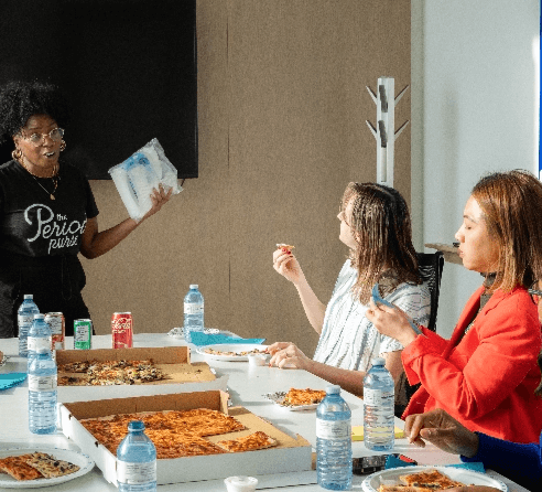 A staff members enjoying a pizza lunch while listening to a presentation